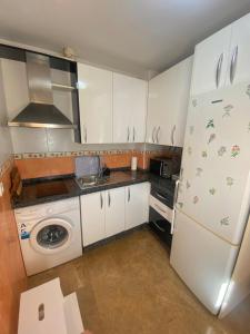 une cuisine avec des armoires blanches et un réfrigérateur blanc dans l'établissement Private terrace & Free Parking, à Malaga