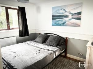Enfield House - Beautiful 2 Bed - Good Transport Free Parking في Enfield Lock: سرير في غرفة نوم مع صورة على الحائط