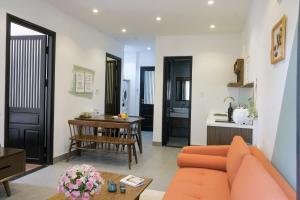 a living room with an orange couch and a kitchen at Quang Vinh Apartment and Hotel Hoi An in Hoi An