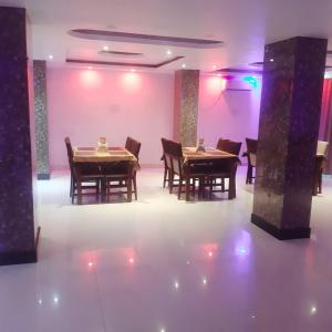 una sala da pranzo con tavoli, sedie e pareti rosa di Hotel Crown Palace a Patna