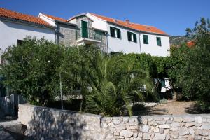 a house with a stone retaining wall and trees at Apartments with a parking space Bol, Brac - 4659 in Bol