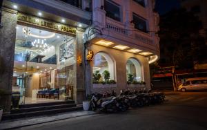 un gruppo di motociclette parcheggiate fuori da un edificio di notte di Golden Legend Palace Hotel a Hanoi
