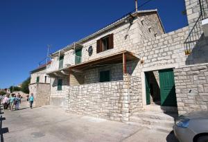 un edificio de piedra con gente parada fuera de él en Apartments by the sea Bol, Brac - 4657 en Bol