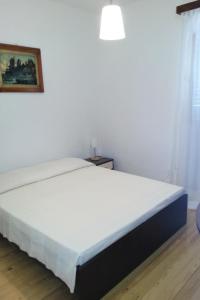 a white bed in a room with a white wall at Apartments by the sea Bol, Brac - 4657 in Bol