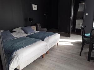 a bedroom with two beds and a chair at La Pomme d'Or in La Charité-sur-Loire