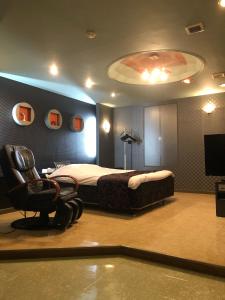 sypialnia z łóżkiem, krzesłem i telewizorem w obiekcie ホテルハンズ w mieście Ginan