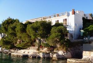 a white house on a hill next to the water at Apartments by the sea Cove Jagodna - Brusje, Hvar - 4619 in Brusje