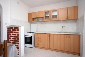 cocina con armarios de madera y horno con fogones en Apartments by the sea Mastrinka, Ciovo - 4648, en Trogir