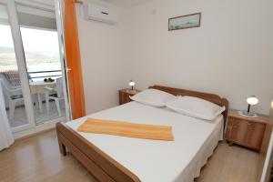 - une chambre avec un lit doté de draps blancs et un balcon dans l'établissement Apartments by the sea Mastrinka, Ciovo - 4648, à Trogir