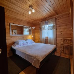 ein Schlafzimmer mit einem Bett in einer Holzhütte in der Unterkunft Revontulen Tupa in Kaamanen