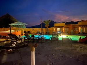 a swimming pool with chairs and umbrellas at night at Los Vientos Hotel in Bahía de los Ángeles