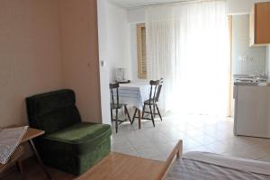 ein Wohnzimmer mit einem grünen Stuhl und einem Tisch in der Unterkunft Studio Palit 3195f in Rab
