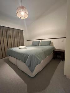 a white bedroom with a large bed and a chandelier at Snowstay at Heidi’s in Smiggin Holes