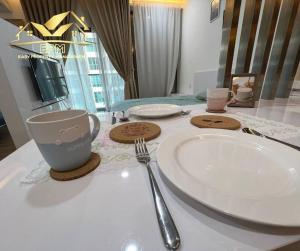 a table with a plate and a cup and a fork at Cheras Menara Simfoni Modern Studio in Cheras