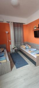 2 camas en una habitación con pared de color naranja en Nagyi Apartman Kecskemét, en Kecskemét