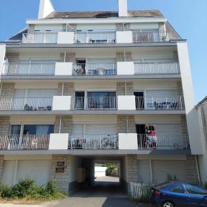 an apartment building with balconies and a car parked in front at Studio proche plages / En couple ou avec enfants in Bénodet