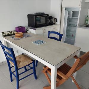 a kitchen with a table with chairs and a microwave at Studio proche plages / En couple ou avec enfants in Bénodet