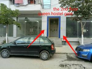 um carro estacionado em frente a uma casa com duas flechas em Queen Hostel em Durrës