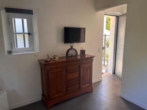 a room with a tv on a wall with a wooden cabinet at CHAMBRE d'HOTES POUR 2 PERSONNES in Peymeinade