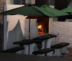 a table and chairs under an umbrella with a fireplace at Bungalows Archi in Termas del Daymán