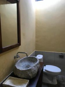 uma casa de banho com um lavatório de pedra e um WC em Panorama Cottage em Bunaken