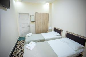 2 letti in una piccola camera con pareti bianche di TINY ART HOUSE HOTEL near Airport of Samarkand a Samarkand