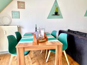 een tafel met groene stoelen en een fles wijn erop bij Eigenes Apartment im Herzen der Stadt mit Balkon und WLAN in Cottbus