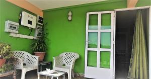 una casa verde con 2 sillas y una puerta en Golden Shell Residence, en Trou d'Eau Douce