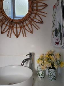 baño con lavabo, espejo y flores en Garden Rest, en New Lambton