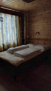 a bed in a room with a wooden wall at Kelomökki Sallatunturissa in Salla