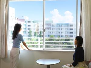 Une femme qui regarde par une fenêtre une fille dans l'établissement Mitsui Garden Hotel Prana Tokyo Bay, à Urayasu