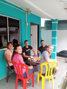 een groep mensen die rond een tafel op een veranda zitten bij Julies Hostel Taman Negara in Kuala Tahan