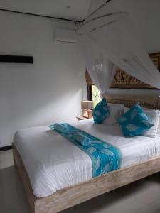 a bedroom with a bed with blue pillows at Villa Gede Private Guest House in Selemadeg