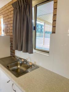 uma cozinha com um lavatório e uma janela em Tallarook Motor Inn em Dubbo