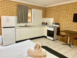 a kitchen with a white refrigerator and a table at Tallarook Motor Inn in Dubbo