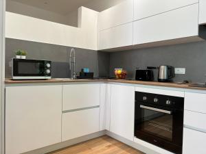 a kitchen with white cabinets and a black oven at Ca' Luciano alloggio a Lido di Venezia in Venice-Lido