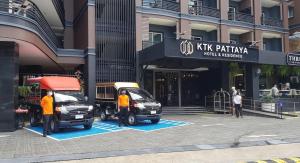 KTK Pattaya Hotel & Residence في باتايا سنترال: سيارتين متوقفتين في موقف للسيارات امام مبنى
