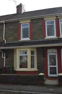 a red brick house with white windows on a street at Entire 3 bedroom house near Caerphilly station in Caerphilly