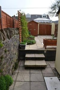 a patio with steps and a stone wall and a fence at Entire 3 bedroom house near Caerphilly station in Caerphilly