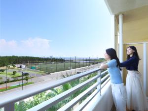 duas mulheres de pé numa varanda com vista para o oceano em Mitsui Garden Hotel Prana Tokyo Bay em Urayasu