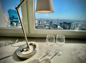 two wine glasses and a lamp in front of a window at Super GREY 2 metro fast WiFi 65’TV Netflix HBO AppleTV+ in Warsaw