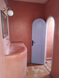 a bathroom with a sink and a white door at RIAD ACACIA in Essaouira