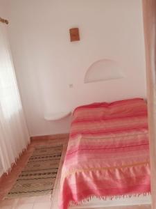 a small bedroom with a bed with a red blanket at RIAD ACACIA in Essaouira