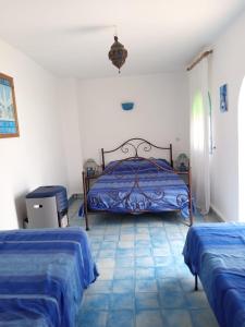 a bedroom with a bed with blue sheets on it at RIAD ACACIA in Essaouira
