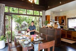 a man standing in a kitchen with a table with food at The Emerald Hill Beach Villa in Mae Nam