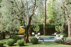 Hotel Piccola Vela في ديسينسانو ديل غاردا: مسبح في حديقة فيها اشجار وشجيرات