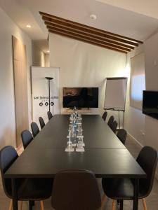 une salle de conférence avec une grande table et des chaises noires dans l'établissement San Lorenzo Suites, à San Lorenzo de El Escorial