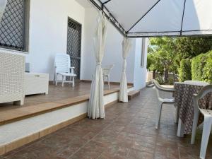 d'une terrasse avec des chaises blanches et une table avec des rideaux. dans l'établissement Casa Alieta, à Torre Lapillo