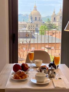 a table with food and drinks and a view of a city at San Lorenzo Suites in San Lorenzo de El Escorial