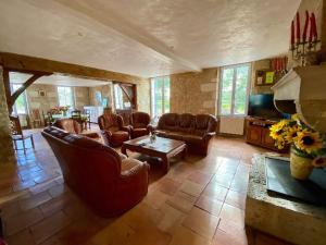 a living room with leather furniture and a tv at Demeure De La Tour in Riocaud